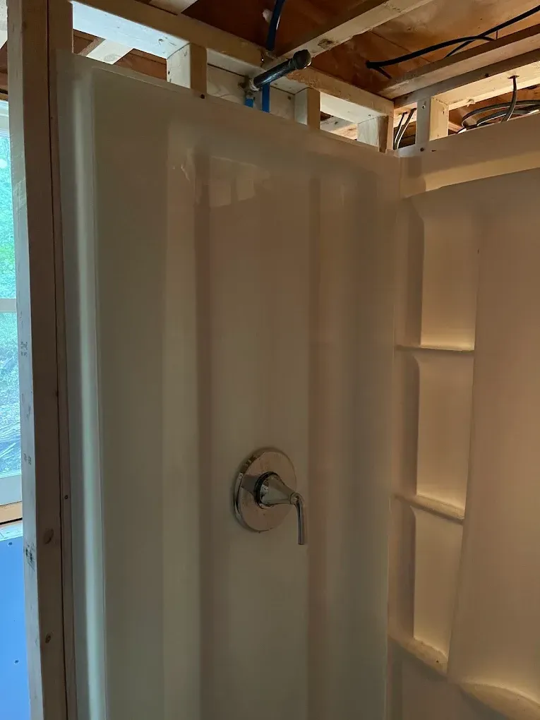 White shower stall with chrome faucet in a bathroom under construction