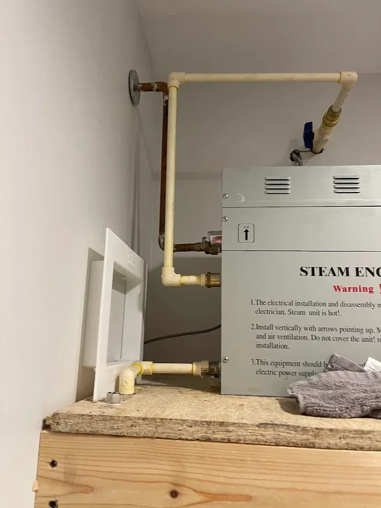 Steam engine equipment with beige pipes mounted on a wall above a wooden surface.