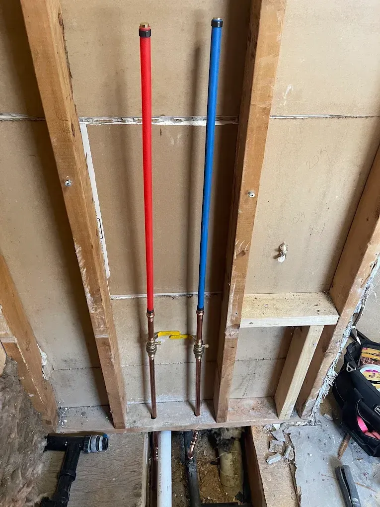 Red and blue pipes installed in a framed wall cavity during renovation.