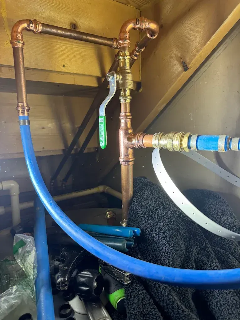 Copper plumbing with blue hoses and valves inside an equipment cabinet.