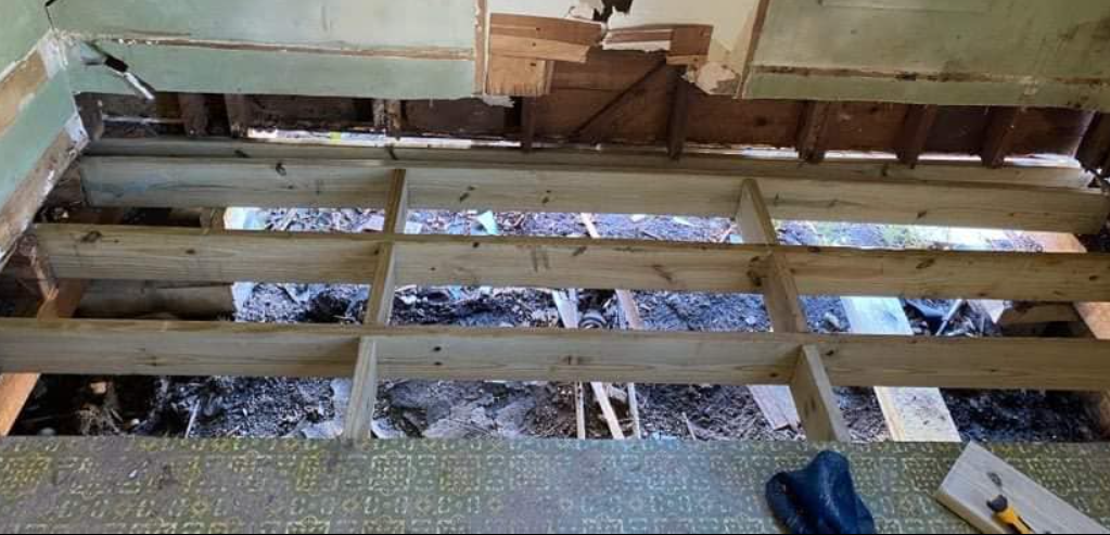 A construction worker is pouring concrete into a hole as part of the house foundation repair. Photo of the house foundation repair for pier and beam.