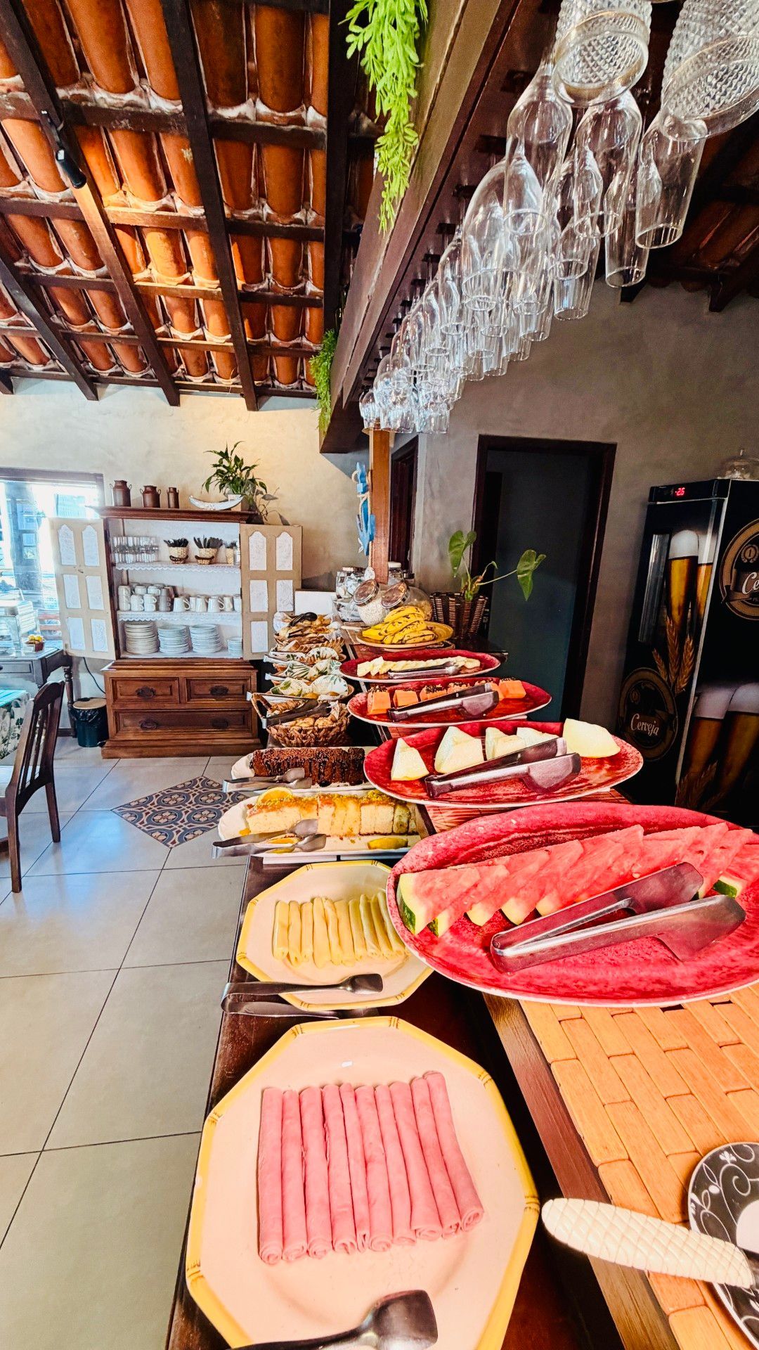 Mesa de buffet com uma variedade de carnes e queijos fatiados numa sala de jantar rústica