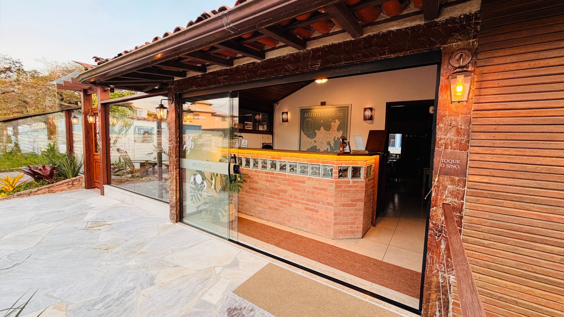 Piscina moderna na cobertura ao lado de um lounge com paredes de vidro e área de estar com vasos de plantas.