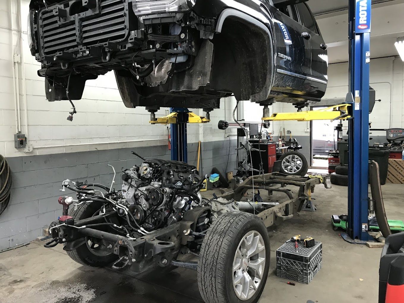 A car is being repaired in a garage with the engine removed.