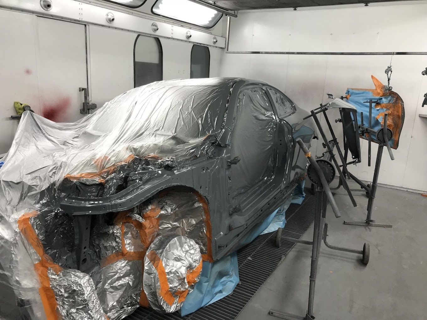 A car is being painted in a paint booth.