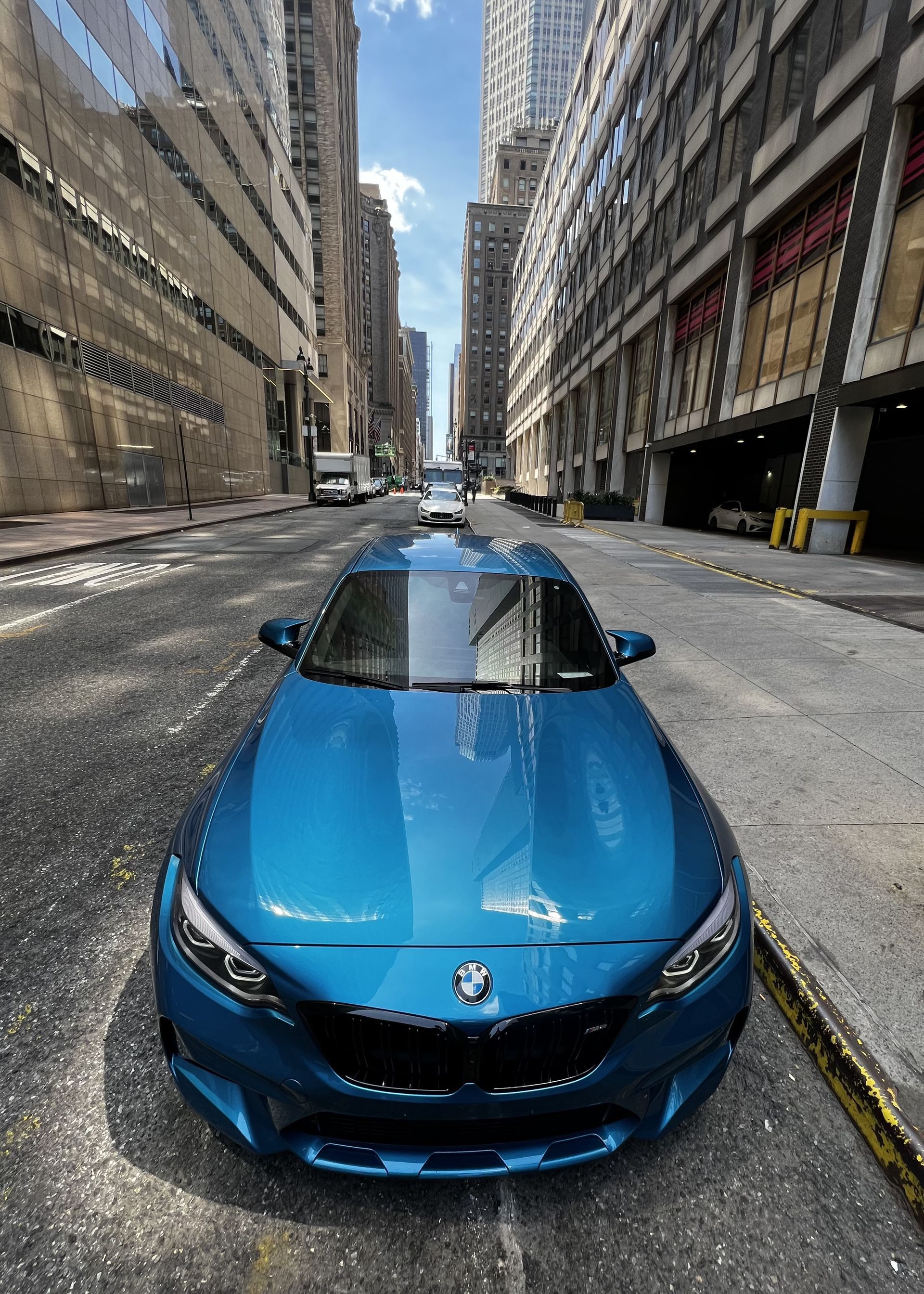 A blue bmw is parked on the side of a city street