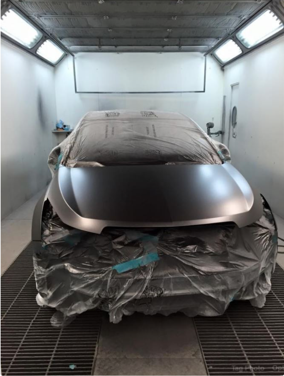 A car is being painted in a paint booth.