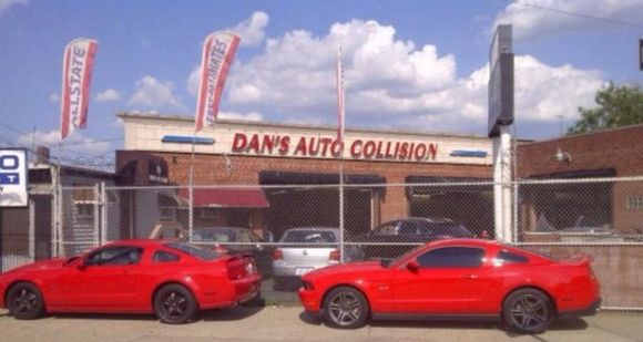 Two red cars are parked in front of dan 's auto collision