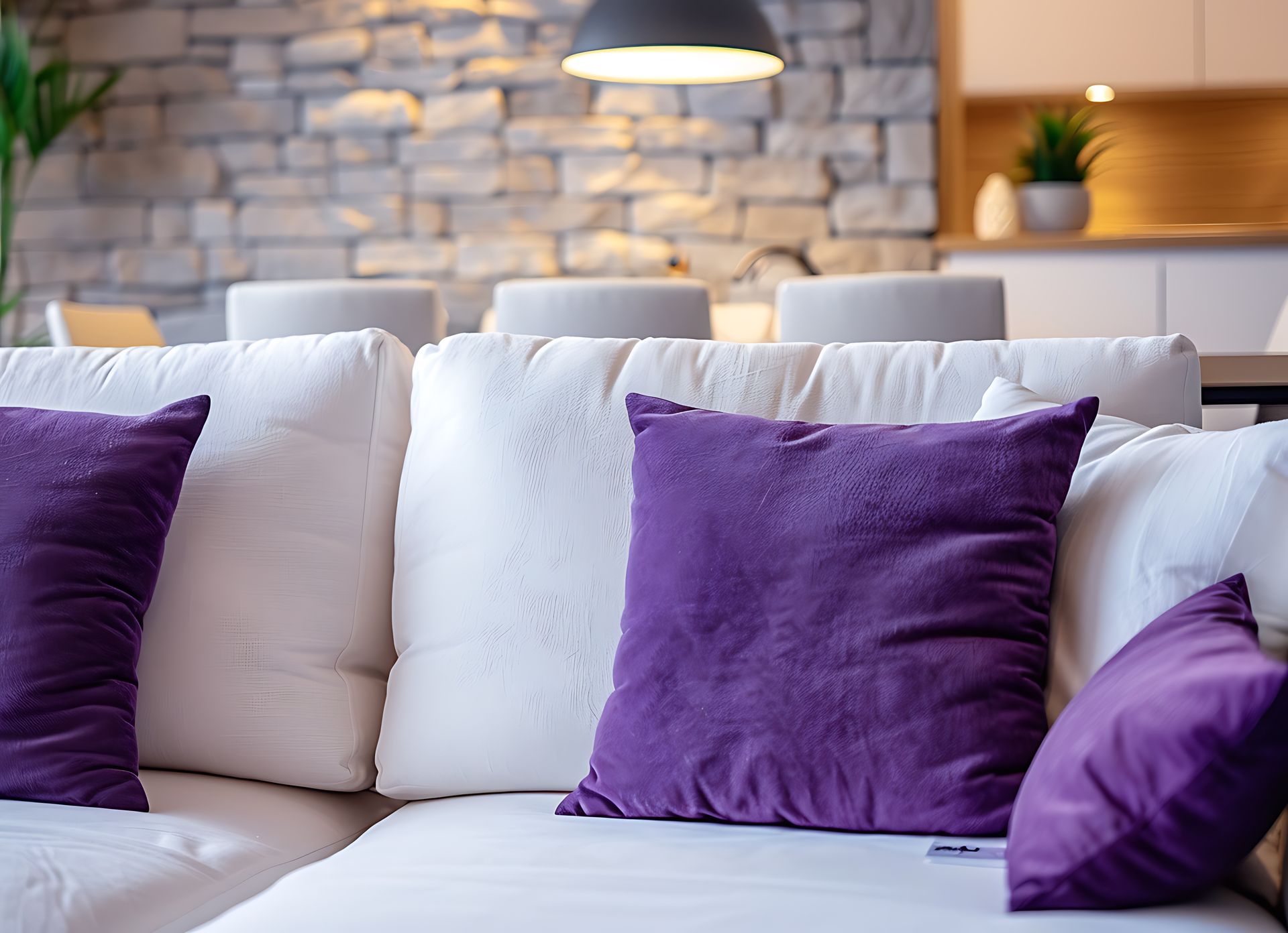 A white couch with purple pillows on it in a living room.