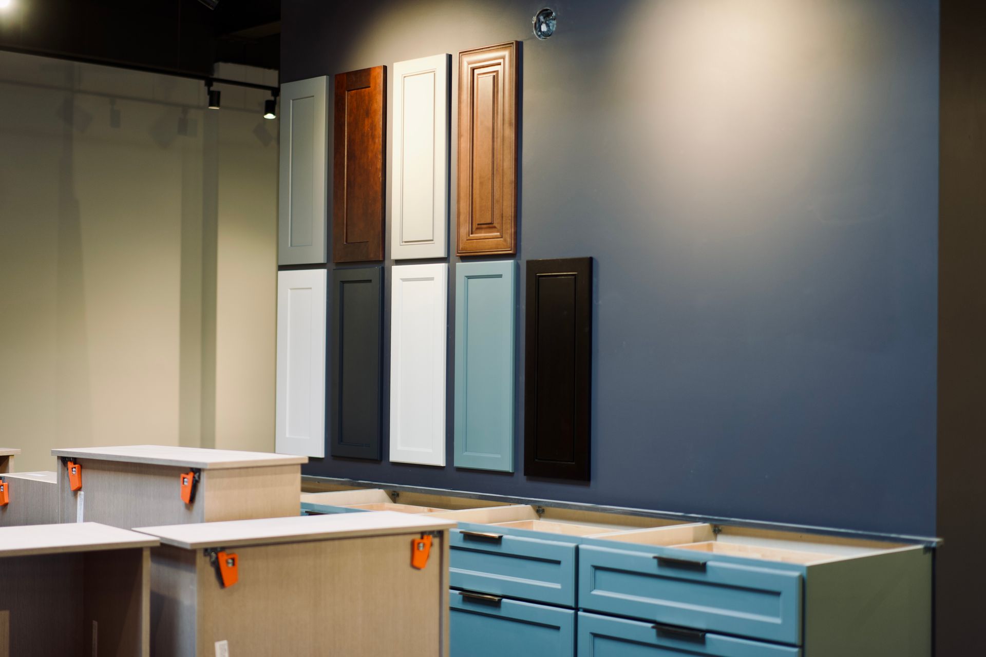 Échantillons de portes d'armoires de cuisine de différentes couleurs présentés sur un mur gris.