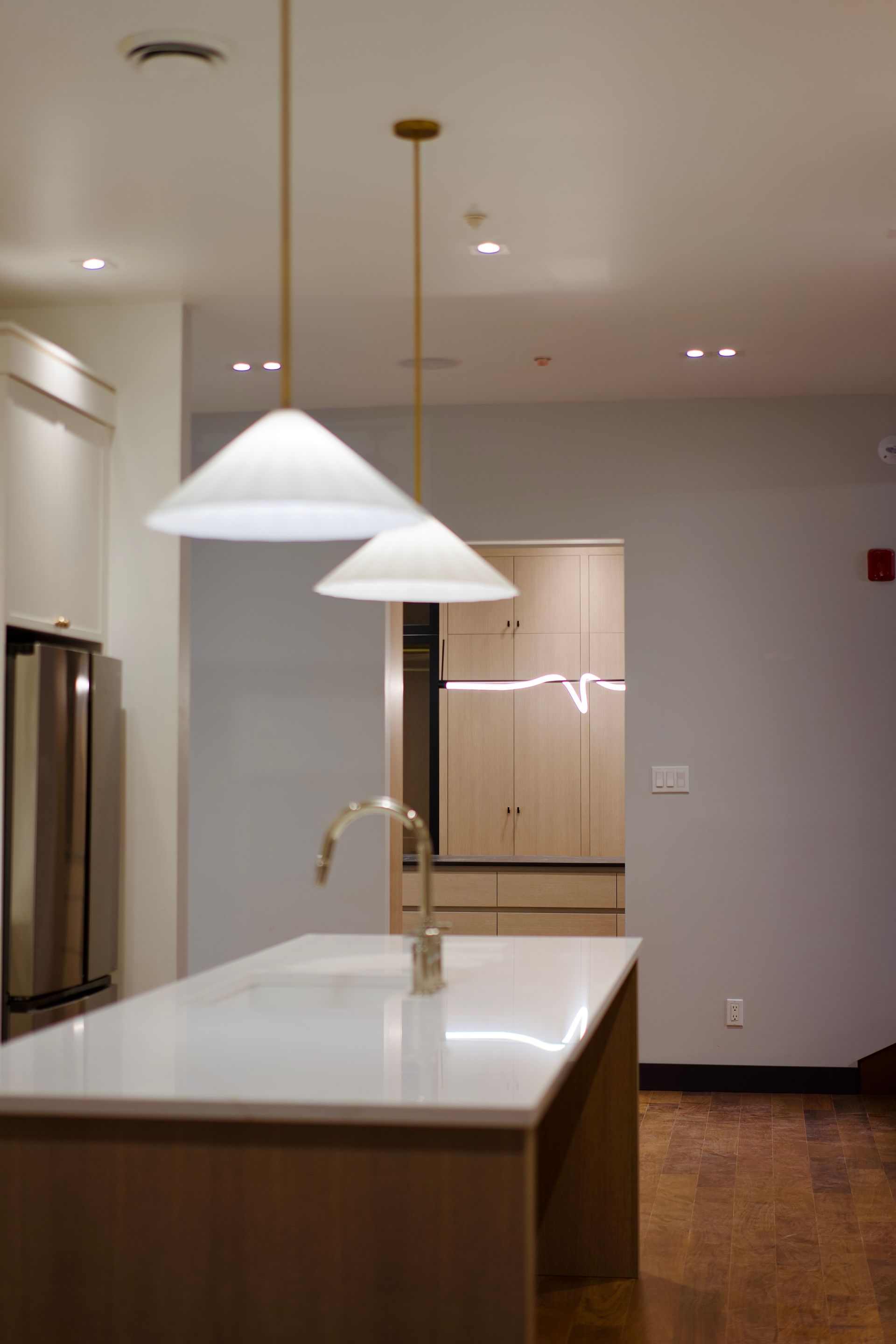 A kitchen with a large island and two lights hanging from the ceiling