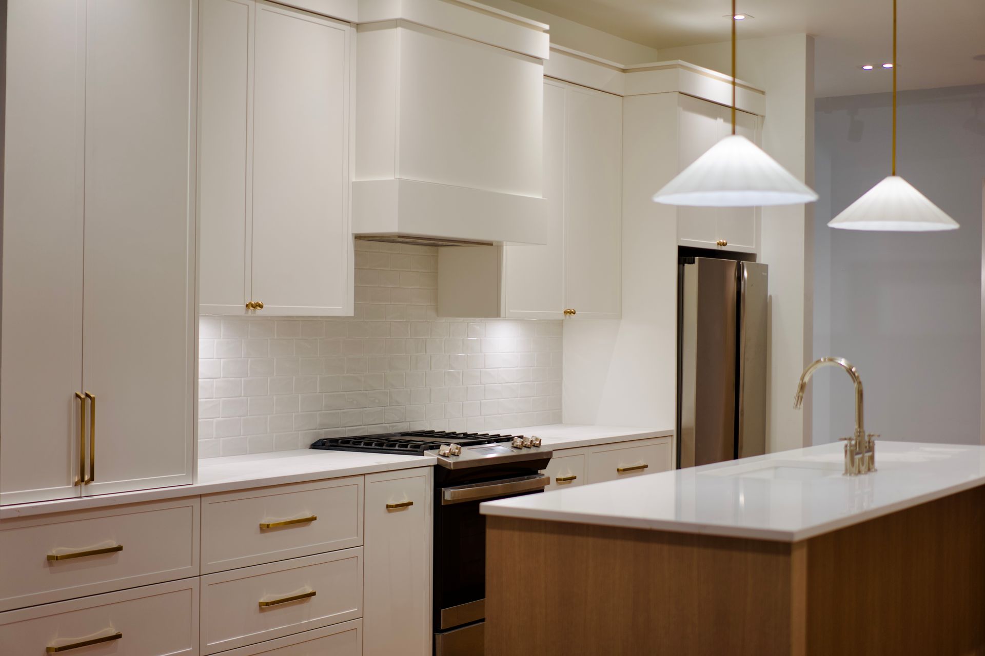 A kitchen with white cabinets , stainless steel appliances , and a large island.