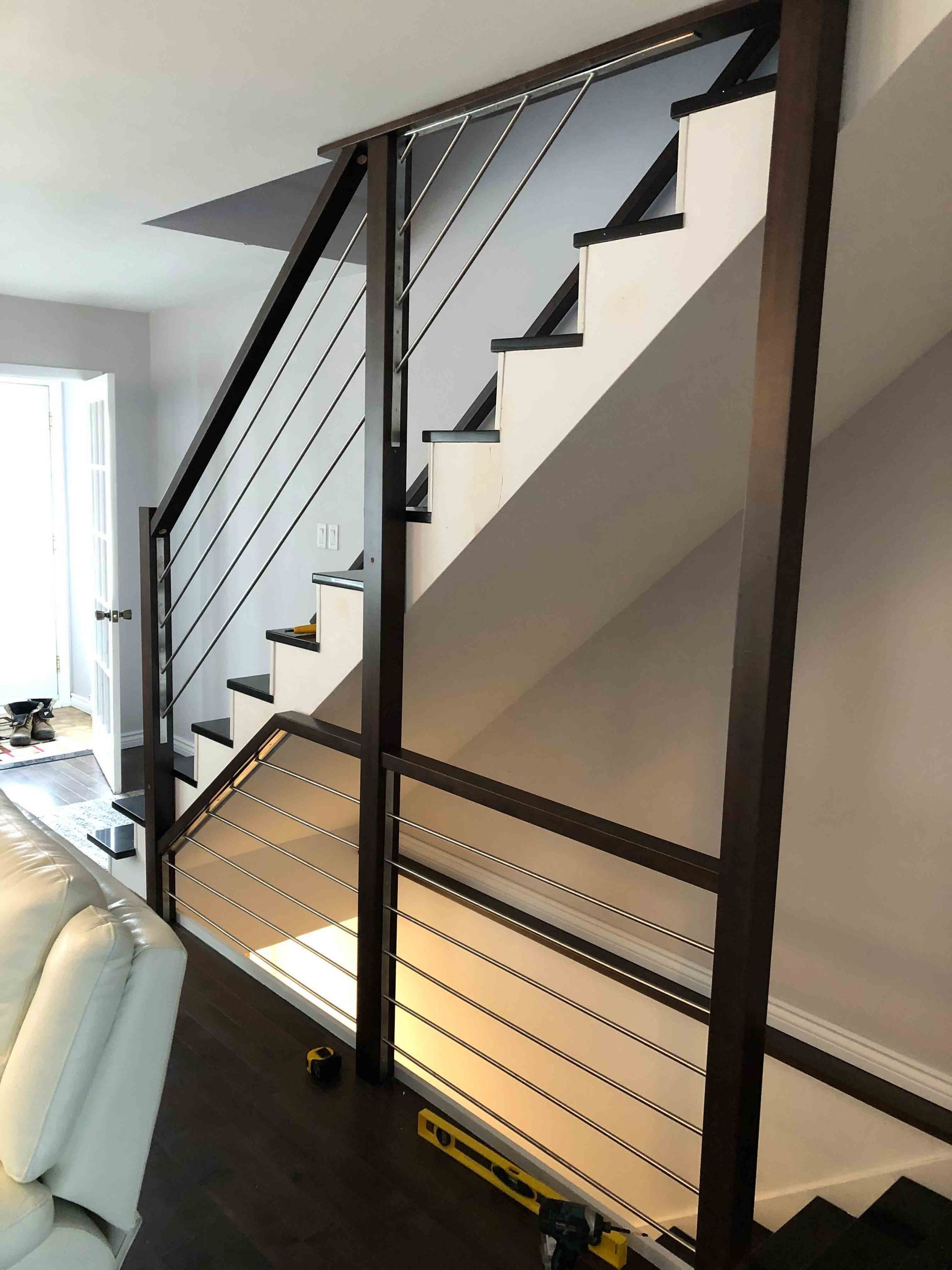 Escalier intérieur moderne avec rampe en métal noir et marches blanches dans une pièce lumineuse