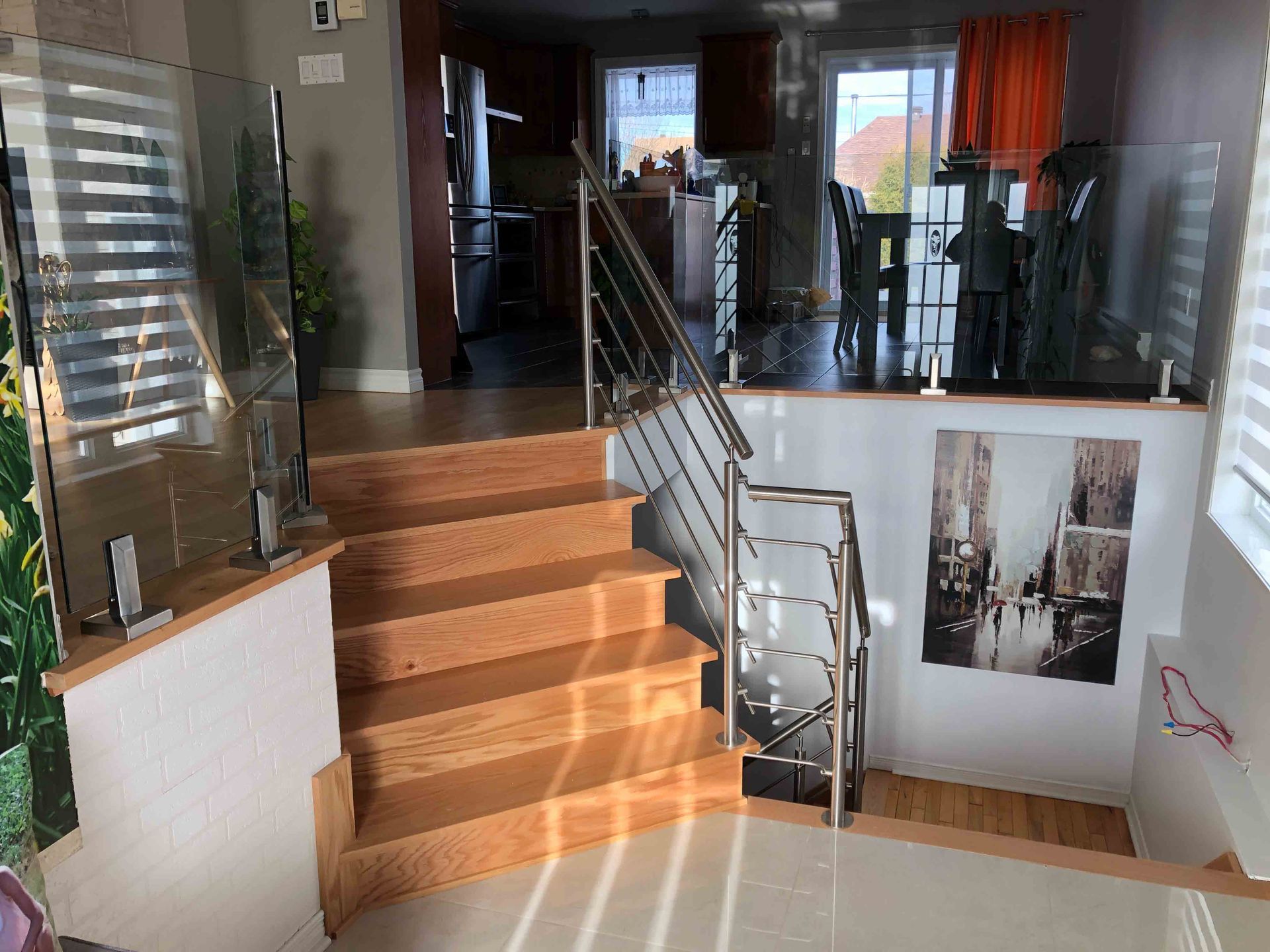 Escalier intérieur moderne avec rampes en verre, marches en bois et palier lumineux