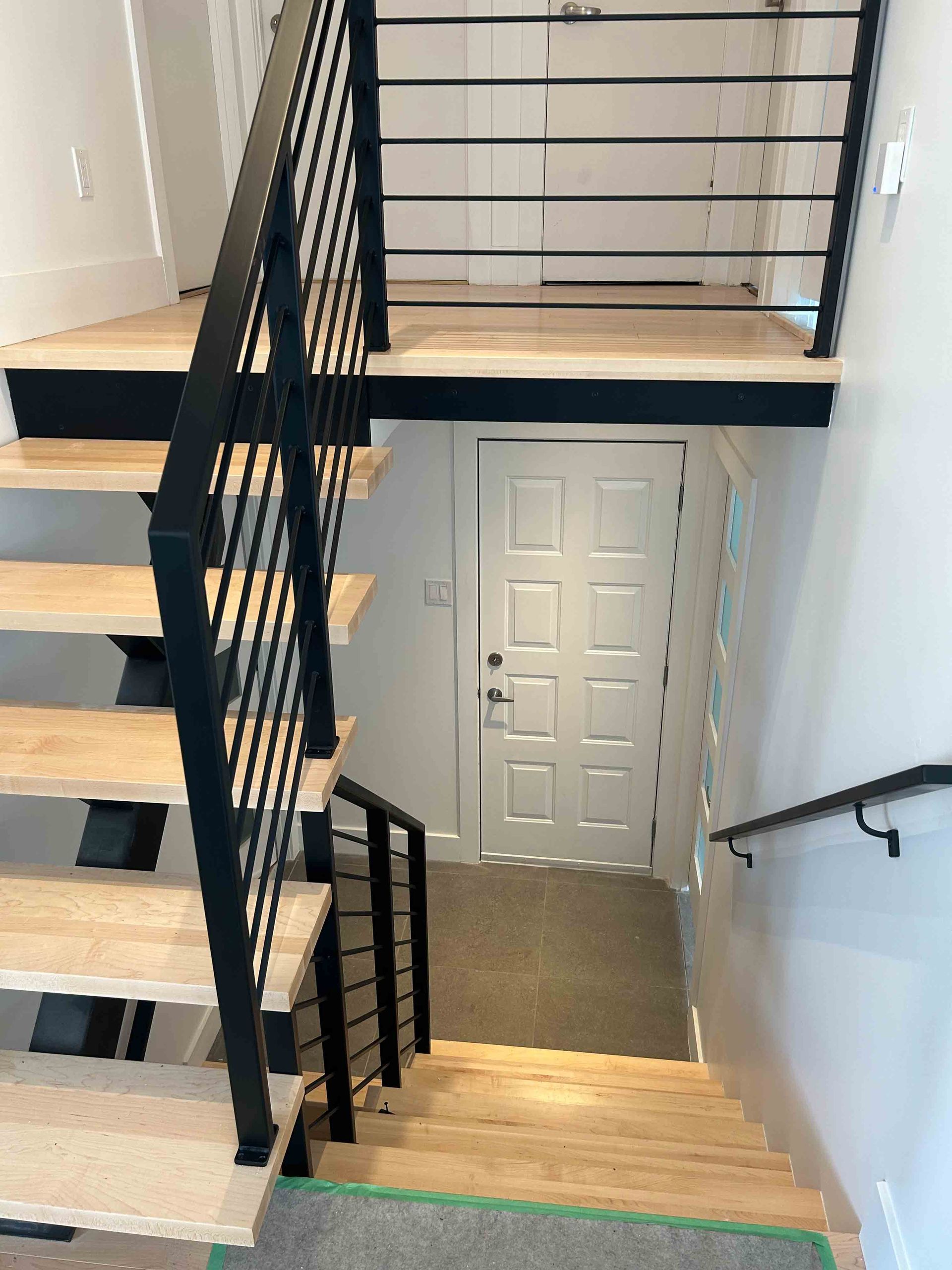 Escalier en bois foncé avec rampes argentées dans une maison moderne.
