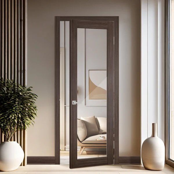 A living room with a couch , vases and a door with a mirror.