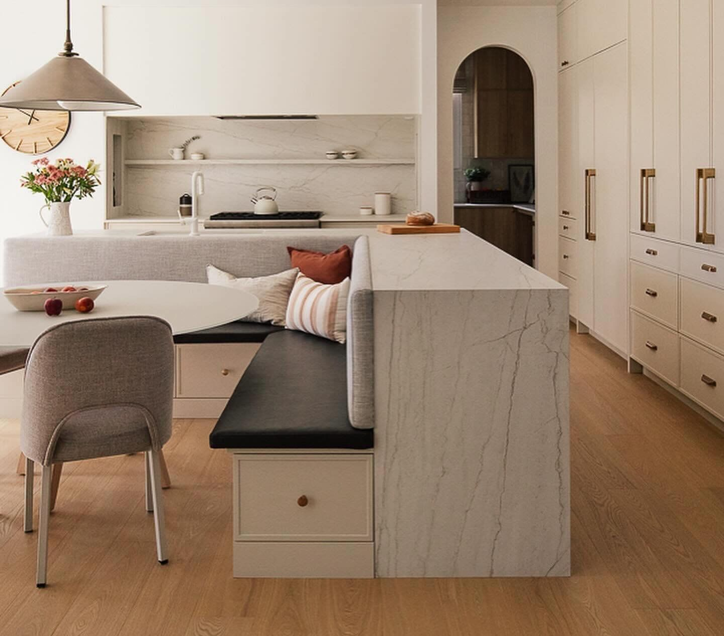 Cuisine moderne avec îlot en marbre, meubles beiges, chaise de salle à manger, canapé et parquet chaleureux