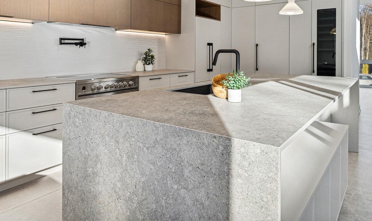 Cuisine moderne avec îlot en terrazzo gris clair et meubles blancs. Intérieur au design minimaliste.
