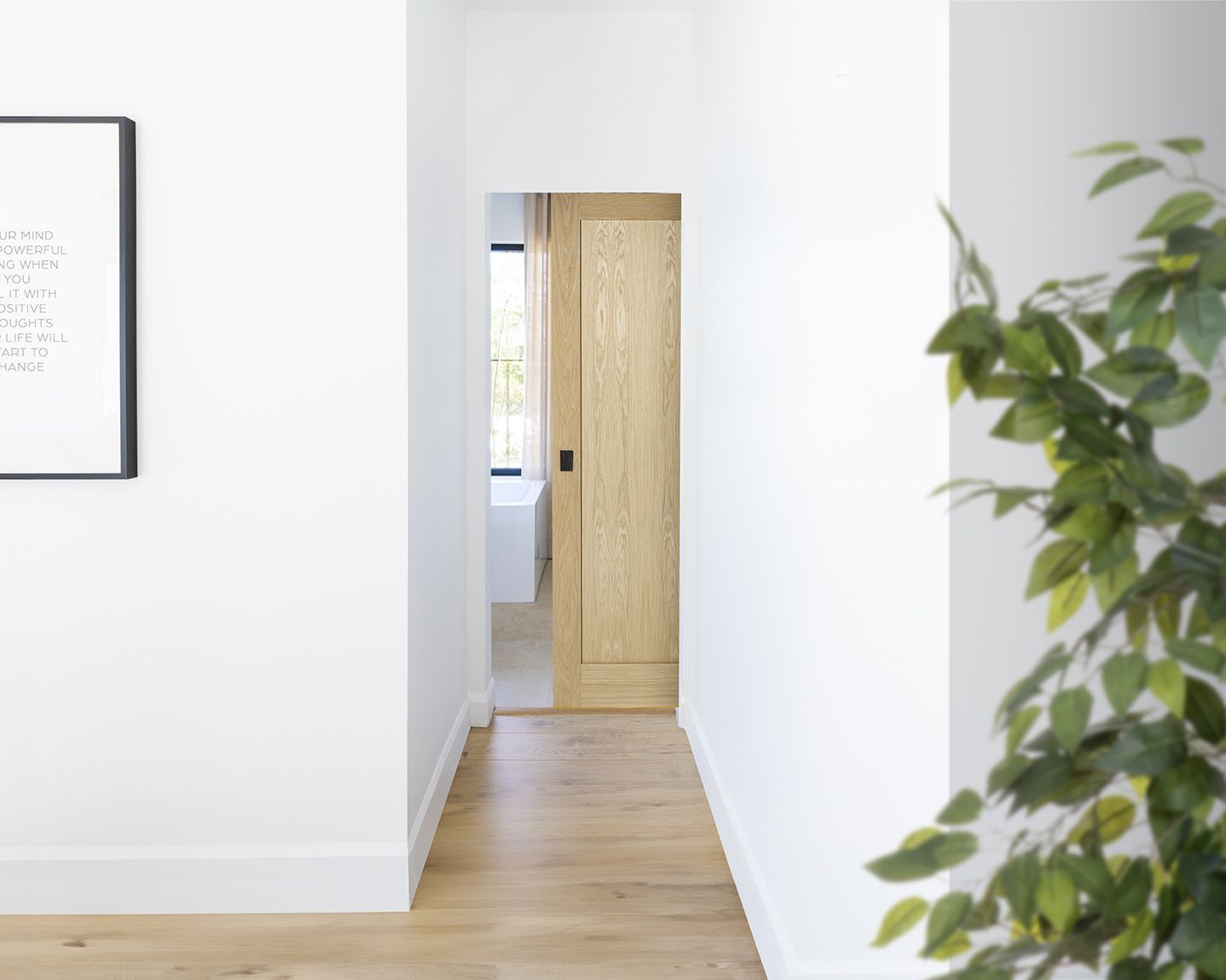 A hallway with a wooden door and a picture on the wall.