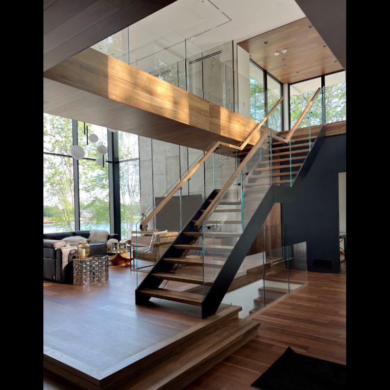 A modern staircase with a glass railing in a living room