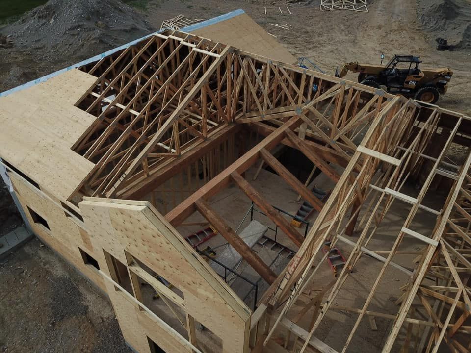 Wooden house under construction; roof trusses being installed.