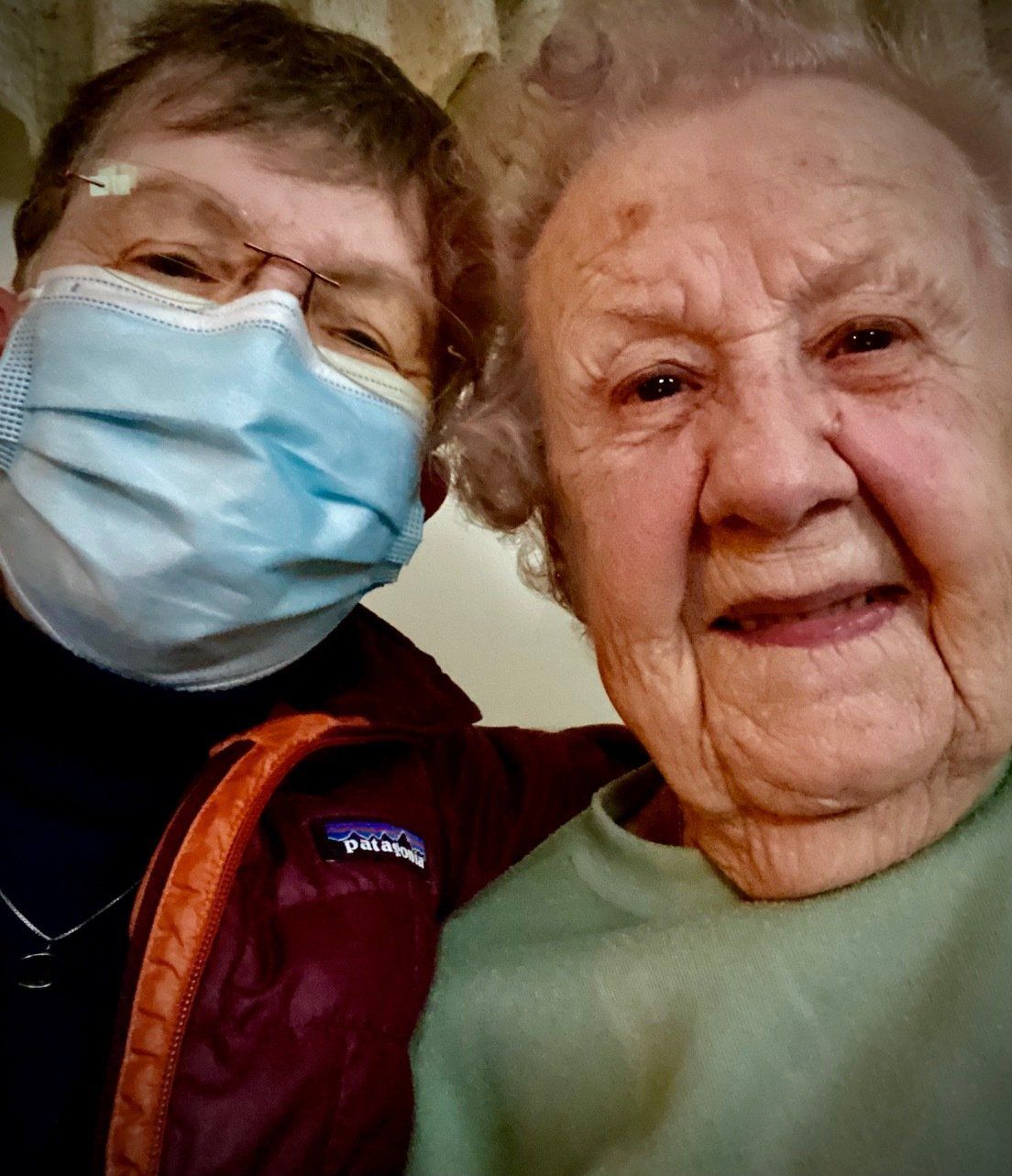A man wearing a mask is posing for a picture with an older woman.