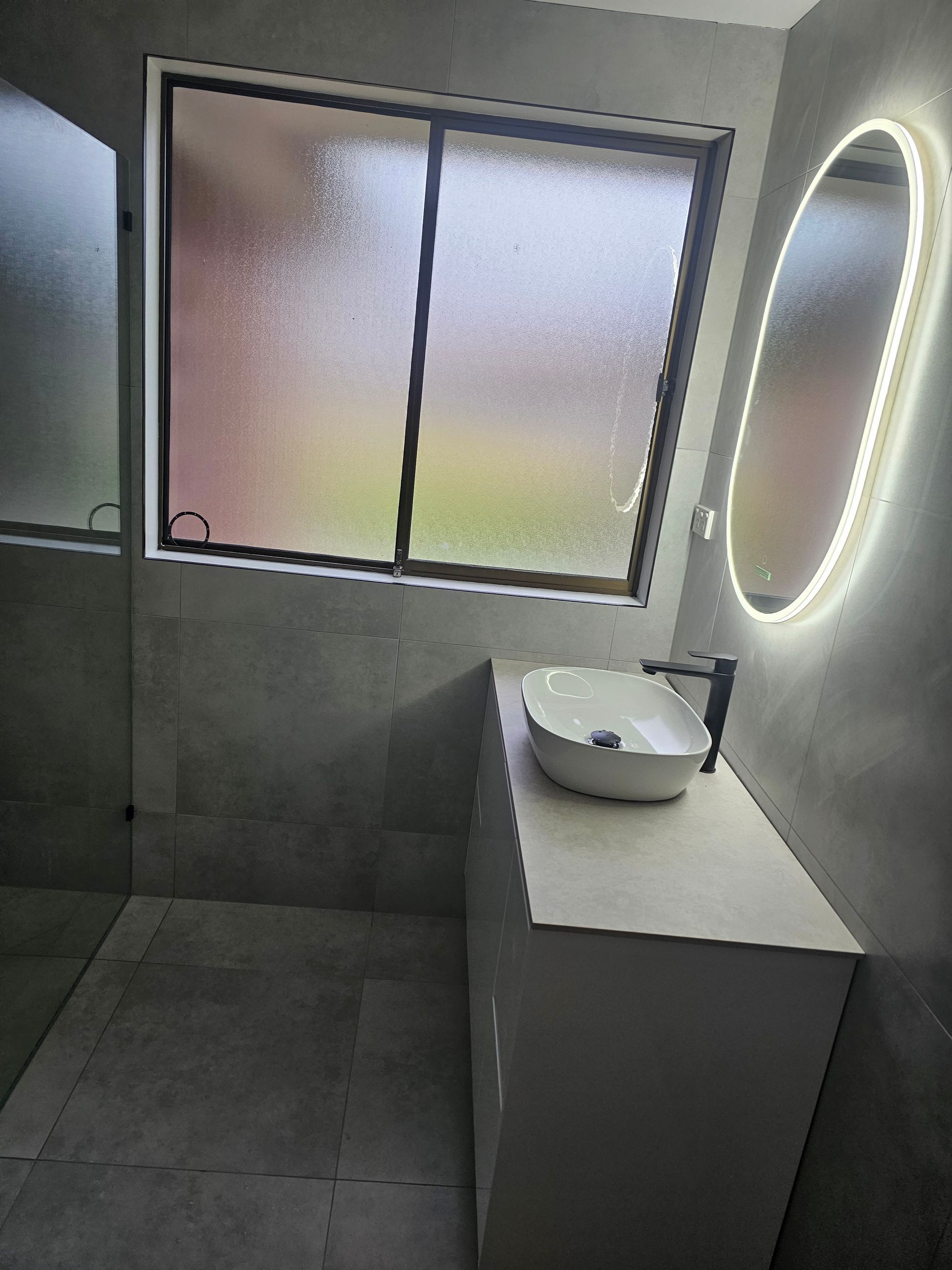 A modern bathroom with a floating white vanity and a frosted glass window — Lenny's Plumbing & Contracting in Granton, TAS