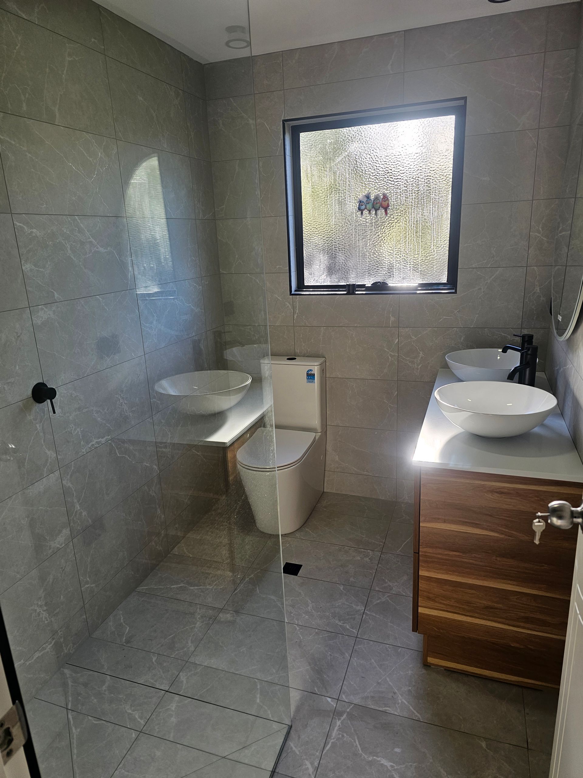 A modern bathroom with grey tiled walls and floor — Lenny's Plumbing & Contracting in Granton, TAS