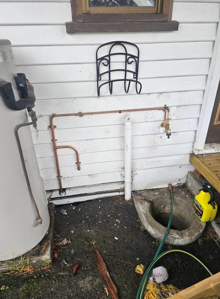 Outdoor Wall with Copper Plumbing Pipes Beside a Septic System on The Ground — Lenny's Plumbing & Contracting in Granton, TAS