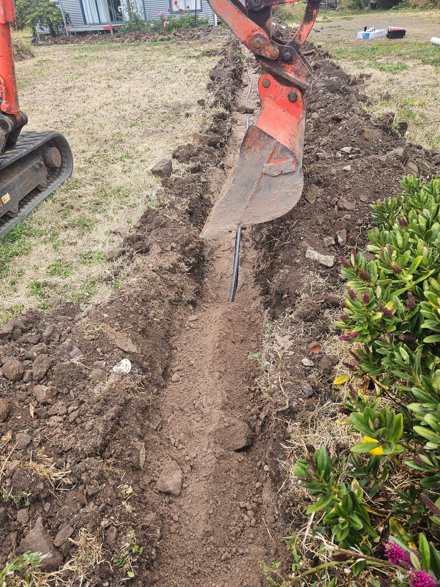 An Orange Excavator Arm Digs a Narrow Trench — Lenny's Plumbing & Contracting in Granton, TAS