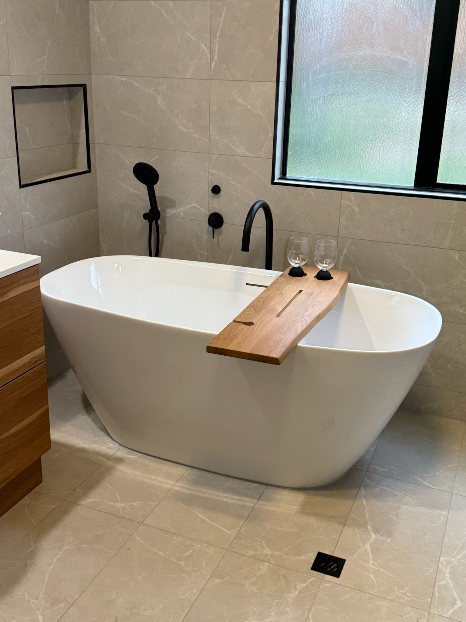 A White Freestanding Bathtub With a Wood Tray — Lenny's Plumbing & Contracting in Granton, TAS