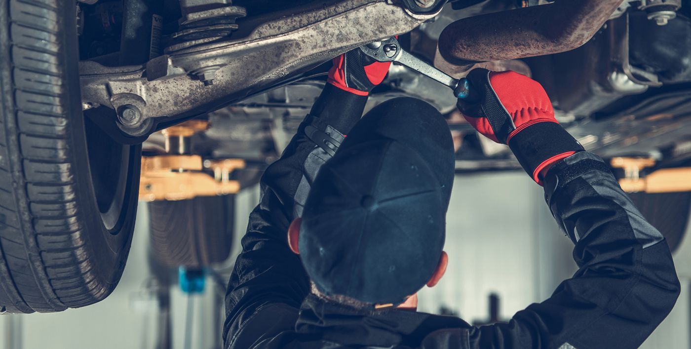 A man is working under a car with a wrench.