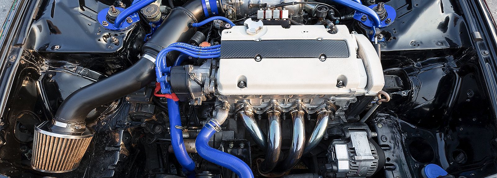A close up of a car engine with blue hoses coming out of it.