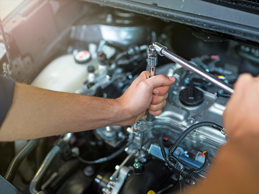 A man is working on a car engine with a wrench.