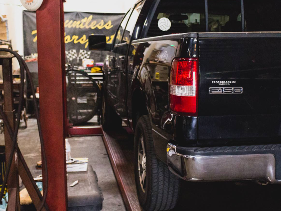 A black ford truck is sitting on a lift in a garage.