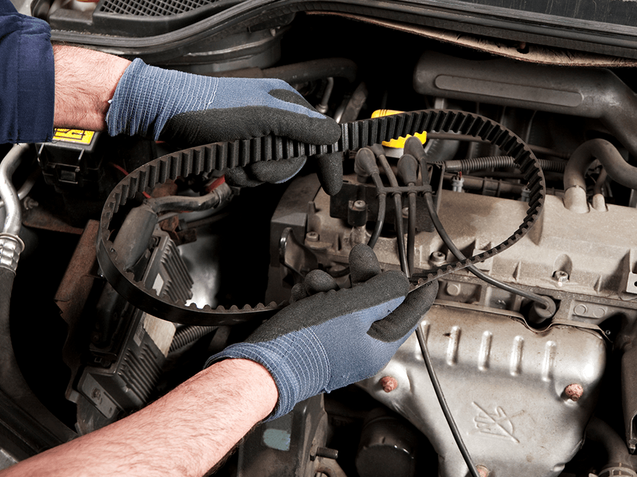 A person is fixing a belt on a car engine.