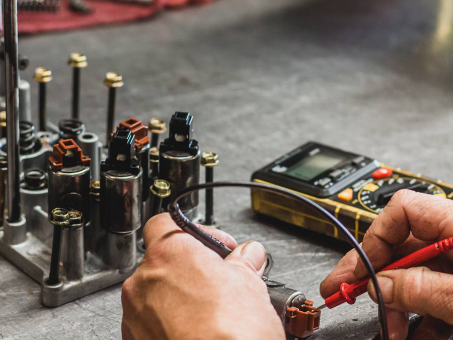 A person is working on a machine with a multimeter.
