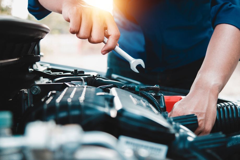 Mechanic using a wrench to repair a car engine in a garage
