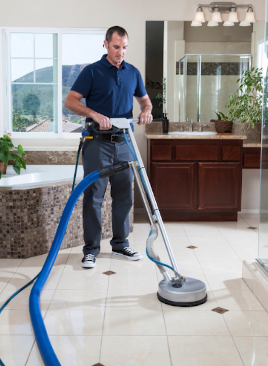 Gloved hand wiping blue tiled floor with a green cloth