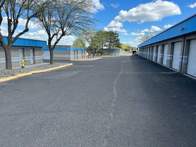 A row of storage units with a blue roof on a sunny day.