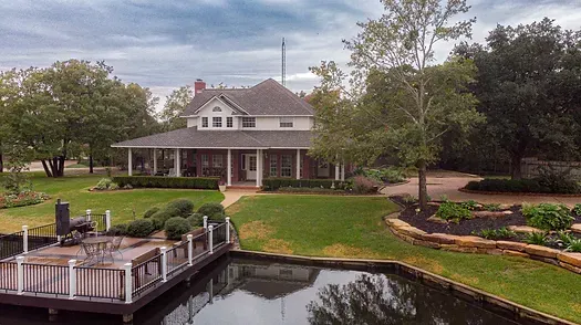 A large house with a dock and a pond in front of it.