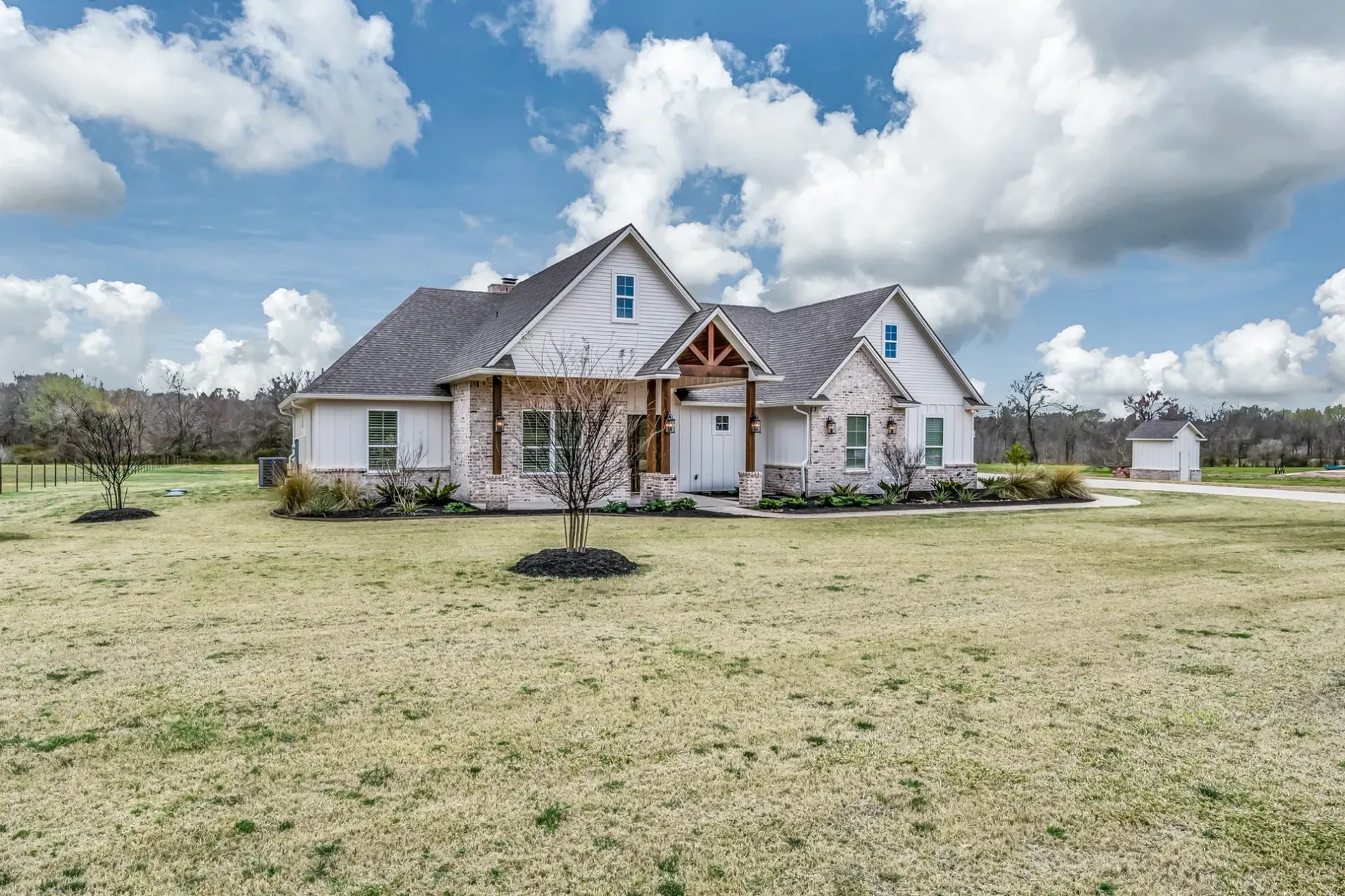 A large white house is sitting on top of a lush green field.