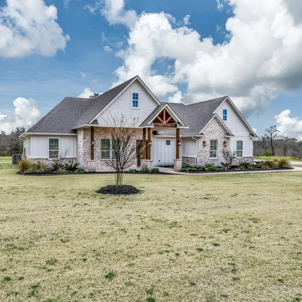 A large white house sits in the middle of a grassy field