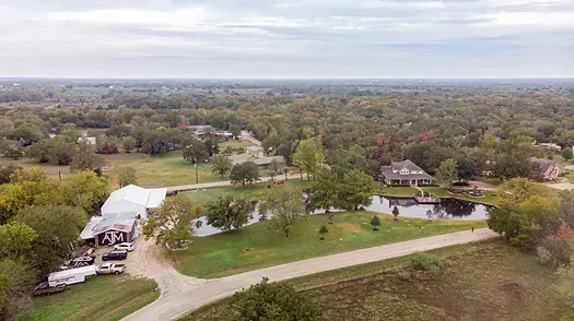 An aerial view of a house surrounded by trees and a lake.