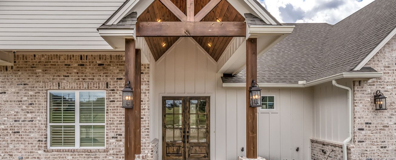 The front of a brick house with a porch and a wooden roof.