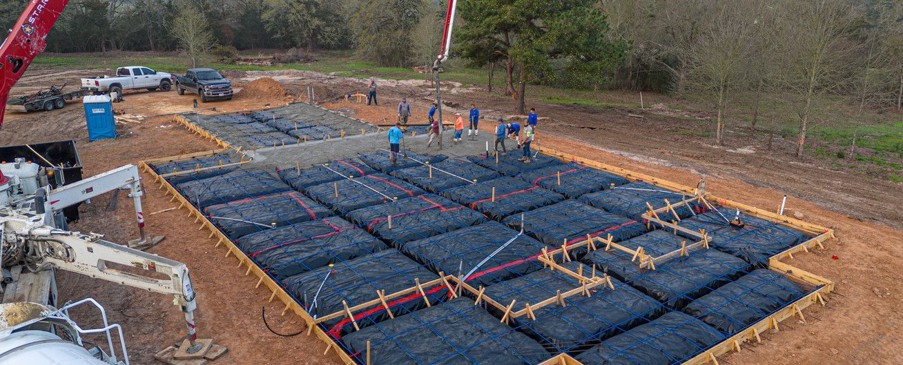 An aerial view of a house foundation being poured with a crane.