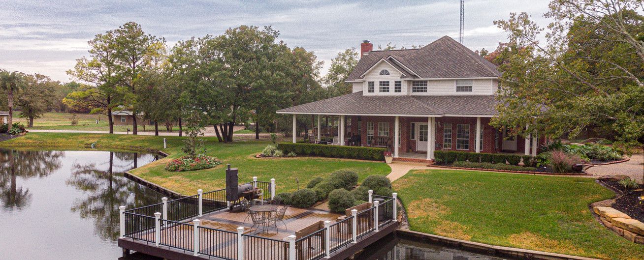 A large house with a dock and a pond in front of it.