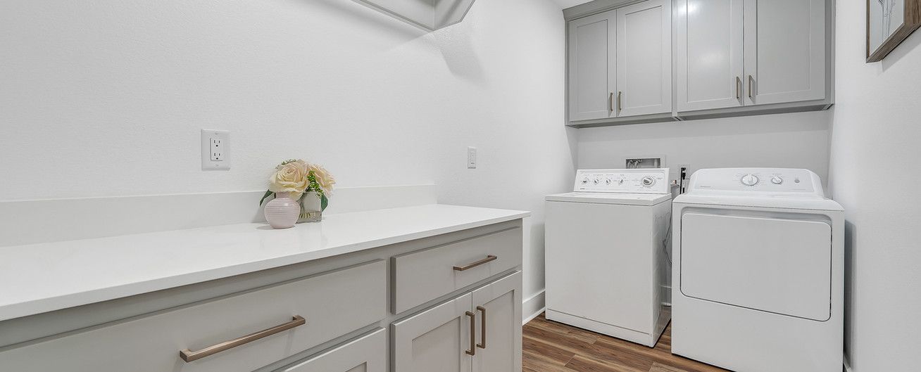A laundry room with a washer and dryer and white cabinets.
