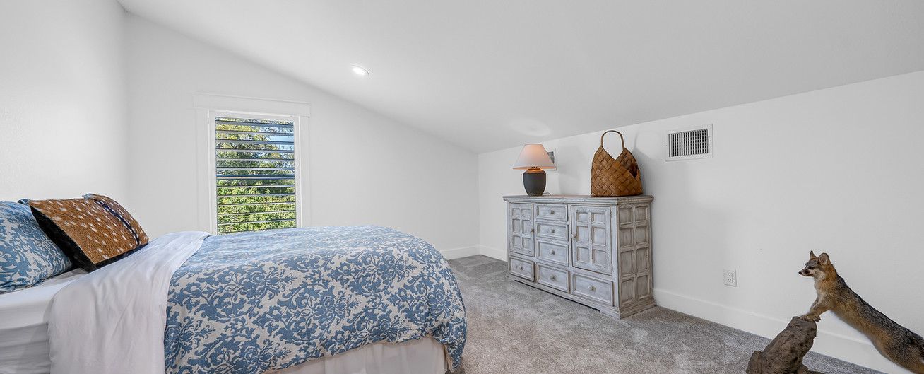 A bedroom with a bed , dresser , and window.