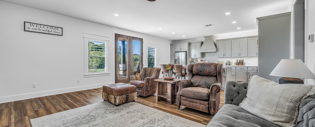A living room with a couch , chairs , ottoman and rug.